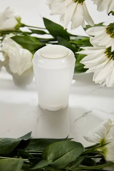 Selective focus of roll on bottle of deodorant with flowers on white surface — Stock Photo