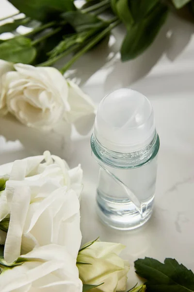 Roll on bottle of deodorant with roses on white surface — Stock Photo