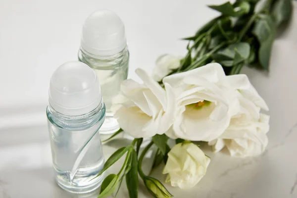 Rollo en botellas de desodorante con rosas en la superficie blanca - foto de stock