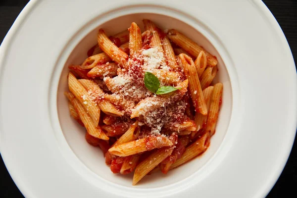 Top view of tasty bolognese pasta with tomato sauce and Parmesan in white plate isolated on black — Stock Photo