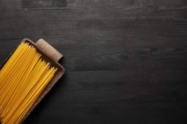 Top view of raw spaghetti on black wooden background — Stock Photo