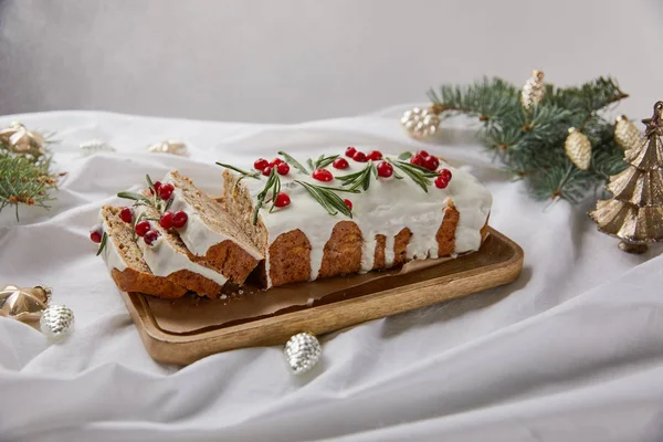 Traditional Christmas cake with cranberry on wooden board near silver baubles and pine needles isolated on grey — Stock Photo