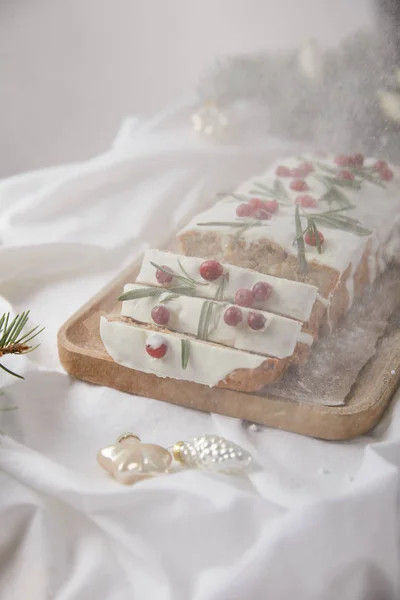 Traditioneller Weihnachtskuchen mit Preiselbeeren auf Holzbrett in der Nähe von Silberkugeln und Tannennadeln isoliert auf grau mit fallendem Schnee — Stockfoto