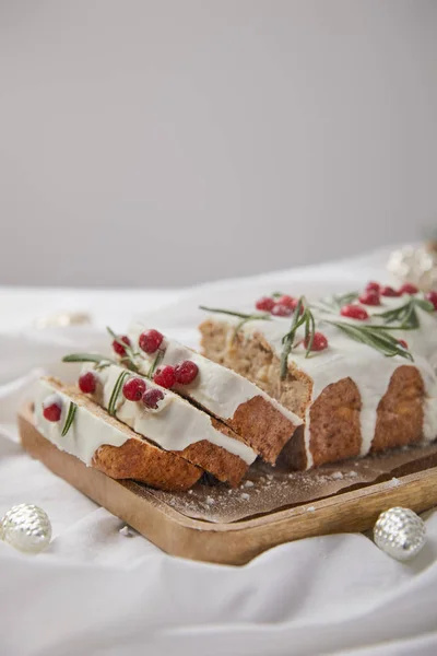 Traditional Christmas cake with cranberry on wooden board near silver baubles isolated on grey — Stock Photo