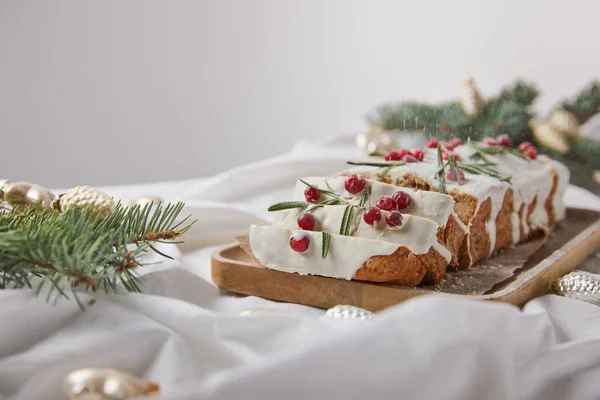 Foco seletivo do bolo de Natal tradicional com cranberry na placa de madeira perto de bugigangas de prata e agulhas de pinho isolado em cinza — Fotografia de Stock