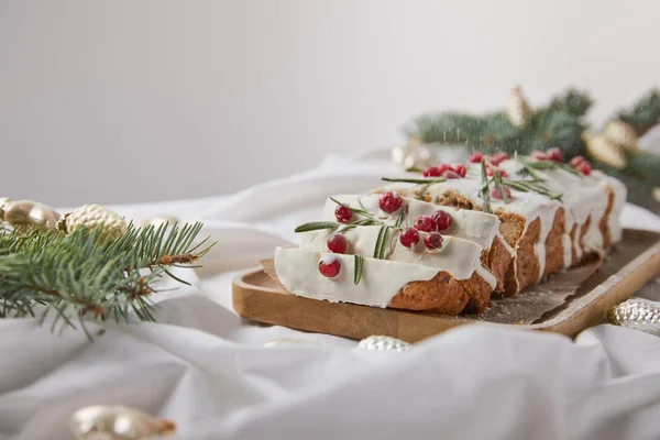 Selektiver Schwerpunkt des traditionellen Weihnachtskuchens mit Preiselbeere auf Holzbrett in der Nähe von Silberkugeln und Tannennadeln isoliert auf grau — Stockfoto