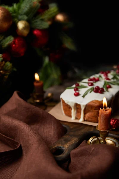 Foco seletivo do bolo de Natal tradicional com cranberry perto de velas em chamas na mesa de madeira — Fotografia de Stock