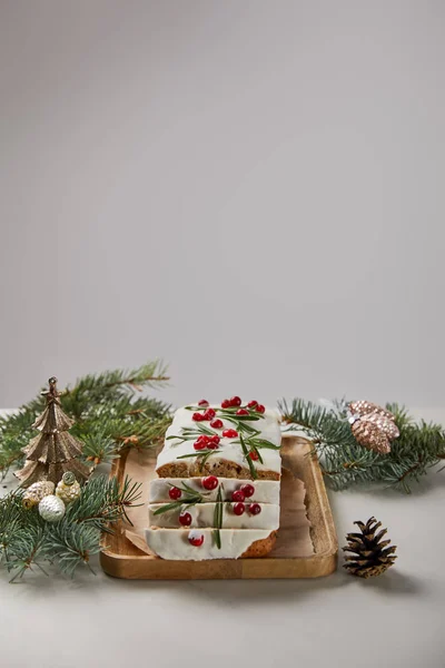 Torta di Natale tradizionale con mirtillo rosso vicino alle bagattelle e pino sul tavolo bianco isolato su grigio — Foto stock