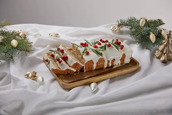 Traditioneller Weihnachtskuchen mit Preiselbeere auf Holzbrett in der Nähe von Silberkugeln und Kiefer isoliert auf grau — Stockfoto