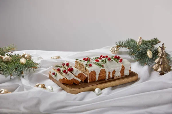 Traditional Christmas cake with cranberry on wooden board near silver baubles and pine isolated on grey — Stock Photo