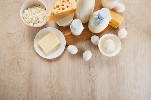Top view of various fresh organic dairy products and eggs on wooden table — Stock Photo