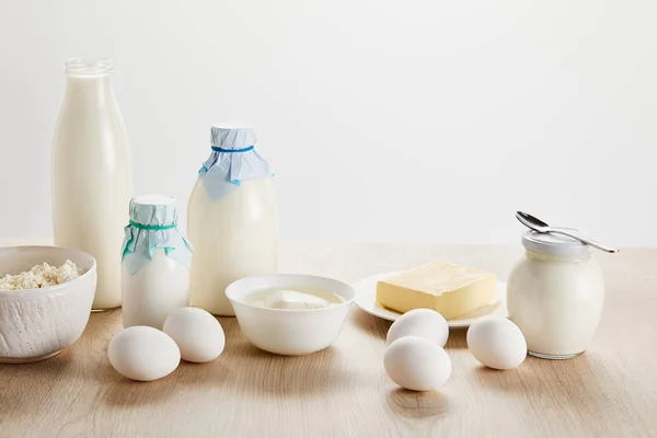 Deliciosos productos lácteos orgánicos y huevos en mesa de madera aislada en blanco - foto de stock