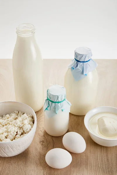 Deliciosos produtos lácteos orgânicos e ovos em mesa de madeira isolada em branco — Fotografia de Stock