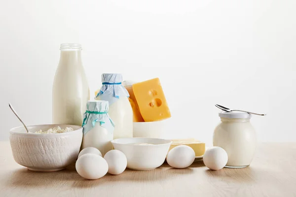 Deliciosos produtos lácteos orgânicos e ovos em mesa de madeira isolada em branco — Fotografia de Stock