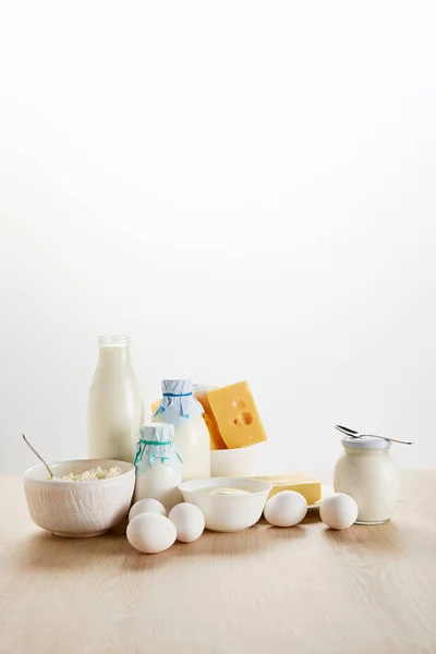 Deliciosos produtos lácteos orgânicos e ovos em mesa de madeira isolada em branco — Fotografia de Stock