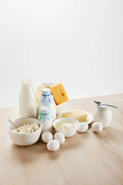 Deliciosos productos lácteos orgánicos y huevos en mesa de madera aislada en blanco - foto de stock