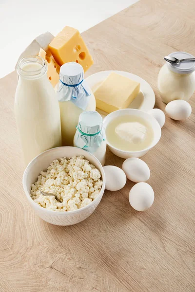 Deliciosos productos lácteos frescos y huevos en mesa de madera aislada en blanco - foto de stock