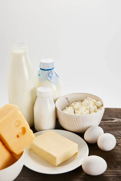 Вкусные свежие молочные продукты и яйца на деревянном столе, изолированные на белом — стоковое фото
