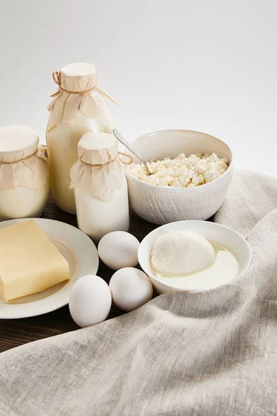 Вкусные свежие молочные продукты и яйца на деревянном столе с тканью, изолированной на белом — стоковое фото