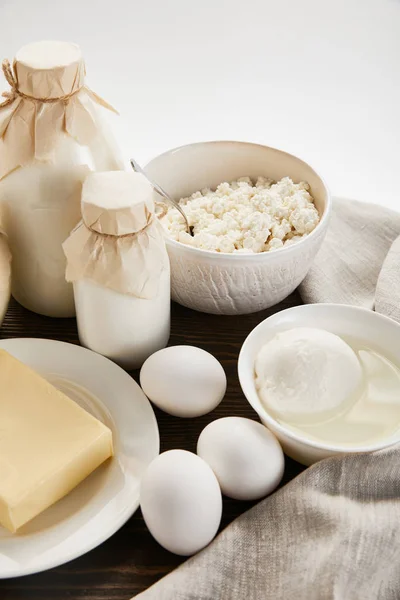 Delicious fresh dairy products and eggs on rustic wooden table with cloth isolated on white — Stock Photo