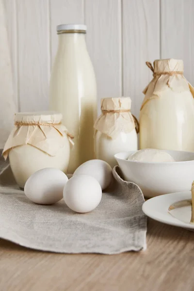 Deliciosos produtos lácteos frescos e ovos em fundo de madeira branca — Fotografia de Stock