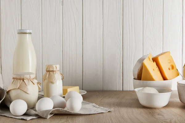 Deliciosos productos lácteos frescos y huevos sobre fondo de madera blanca - foto de stock