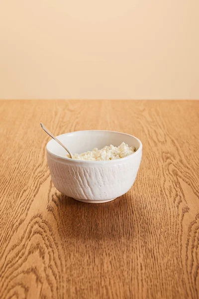 White fresh organic cottage cheese in bowl on rustic wooden table isolated on beige — Stock Photo