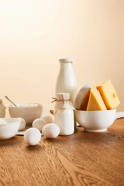Saborosos produtos lácteos orgânicos e ovos em mesa de madeira rústica isolada em bege — Fotografia de Stock