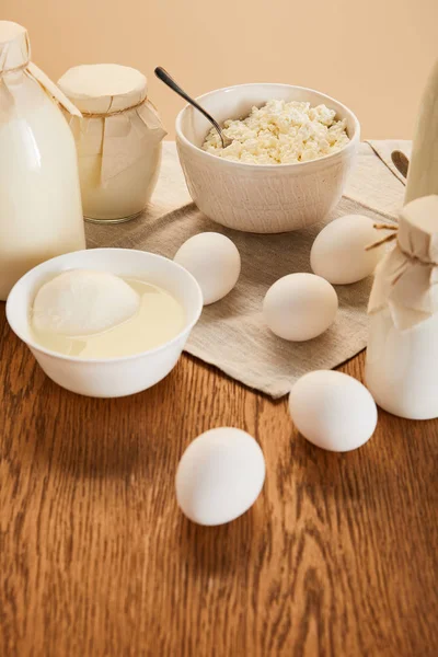 Tasty organic dairy products and eggs on rustic wooden table isolated on beige — Stock Photo