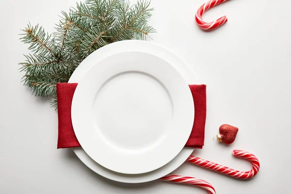 Vista dall'alto della tavola natalizia festiva allestita su sfondo bianco con ramo di pino e caramelle — Foto stock