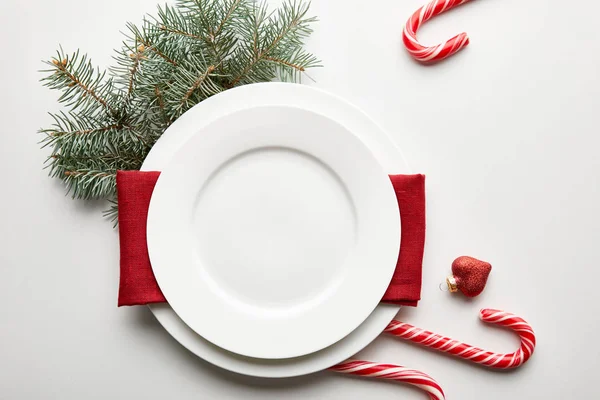 Vista superior de la mesa de Navidad festiva sobre fondo blanco con rama de pino y caramelos - foto de stock