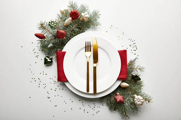 Vue du dessus du décor de table de Noël sur fond blanc avec branche de pin décorée et confettis — Photo de stock