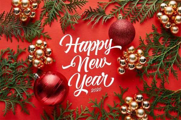 Vista superior de la decoración brillante de Navidad y thuja sobre fondo rojo con letras feliz año nuevo - foto de stock