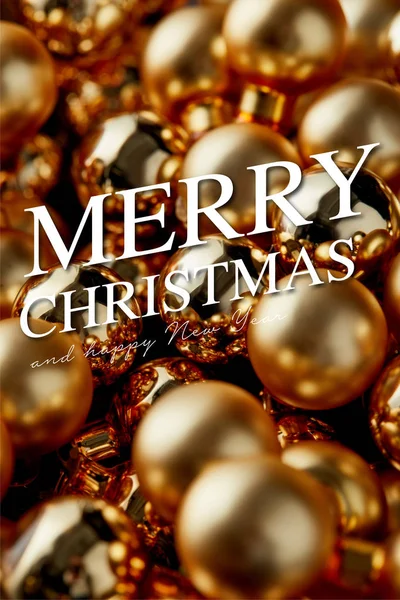 Vista de cerca de brillantes adornos dorados de Navidad con la ilustración de Feliz Navidad - foto de stock