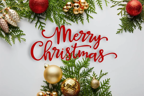 Marco de brillante decoración de Navidad dorada y roja en ramas de thuja verde aisladas en blanco con ilustración de Feliz Navidad - foto de stock