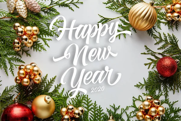 Marco de brillante decoración de Navidad dorada y roja en ramas de thuja verde aislado en blanco con letras feliz año nuevo - foto de stock