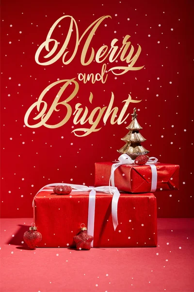 Red gift boxes and decorative golden Christmas tree with baubles on red background with merry and bright golden lettering — Stock Photo