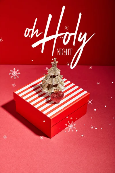 Caja de regalo roja rayada y árbol de Navidad dorado decorativo con adorno sobre fondo rojo con ilustración de la noche santa - foto de stock