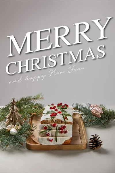 Traditional Christmas cake with cranberry near baubles and pine on white table isolated on grey with merry Christmas and happy new year lettering — Stock Photo