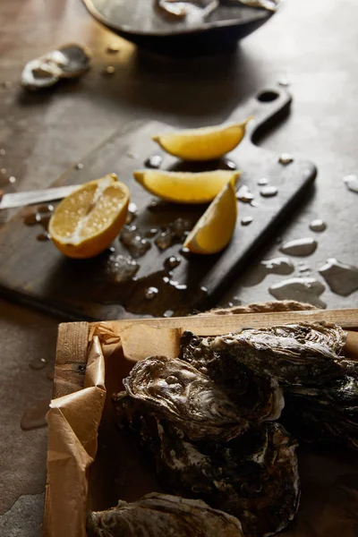 Selective focus of tasty oysters in shell near cutting board and melting ice — Stock Photo