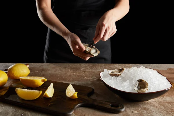 Vue recadrée d'une femme tenant une fourche près d'une huître isolée sur fond noir — Photo de stock