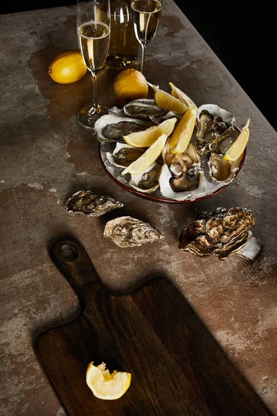 Copas de champán con vino espumoso cerca de botella, ostras y limones en tazón - foto de stock