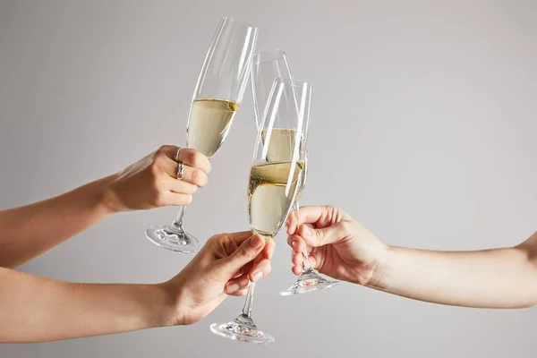 Cropped view of women toasting champagne glasses with sparkling wine isolated on grey — Stock Photo