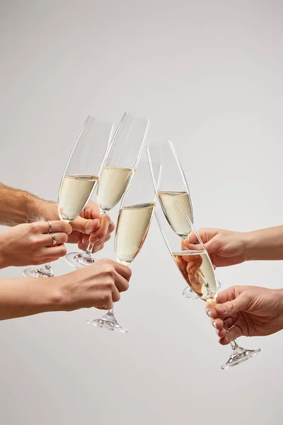 Vue recadrée d'hommes et de femmes grillant des verres à champagne avec du vin mousseux isolé sur gris — Photo de stock