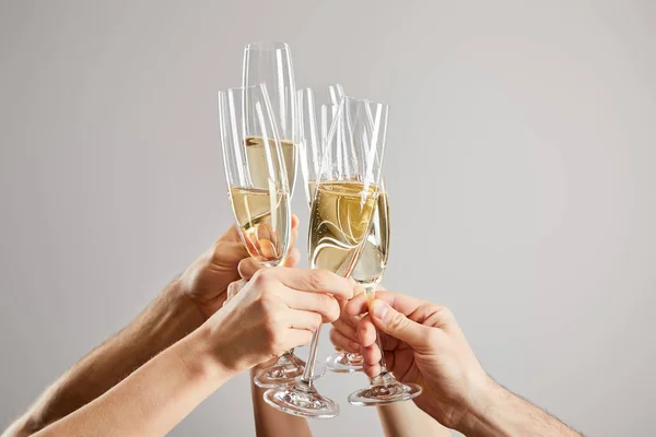 Cropped view of men and women toasting champagne glasses with fresh sparkling wine isolated on grey — Stock Photo