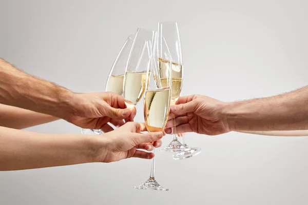 Cropped view of men and women toasting while holding champagne glasses with sparkling wine isolated on grey — Stock Photo