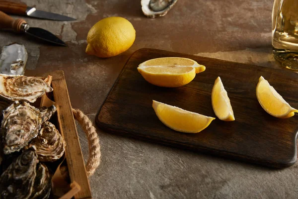 Selective focus of delicious oysters in shells near lemons on wooden cutting board — Stock Photo