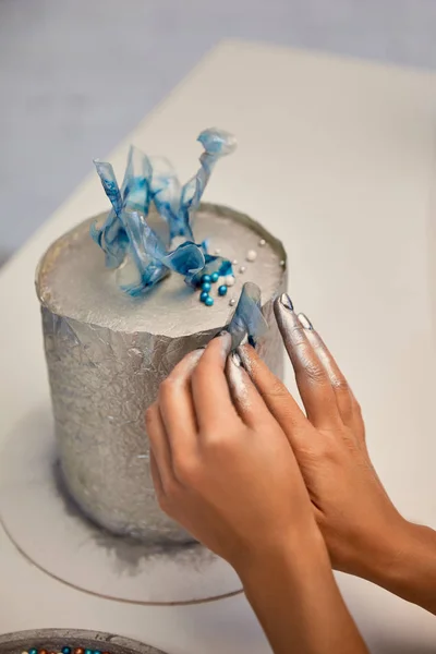 Cropped view of confectioner decorating cake on board — Stock Photo