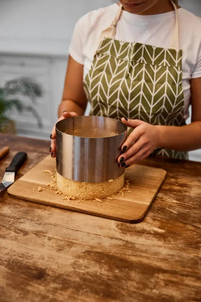 Vista recortada del confitero sacando de la torta del molde de pastel - foto de stock