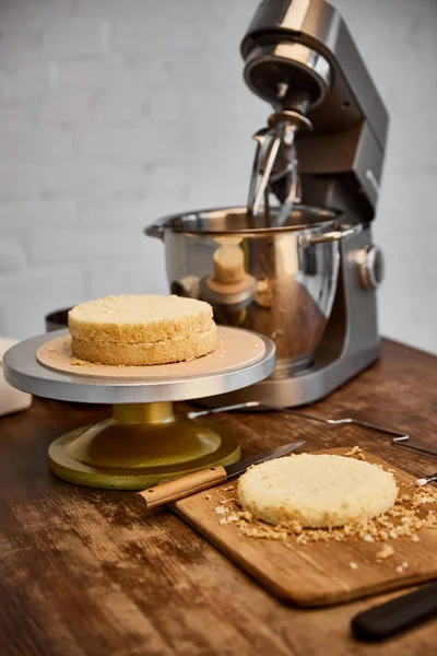 Table with cooking utensils and sponge cake — Stock Photo